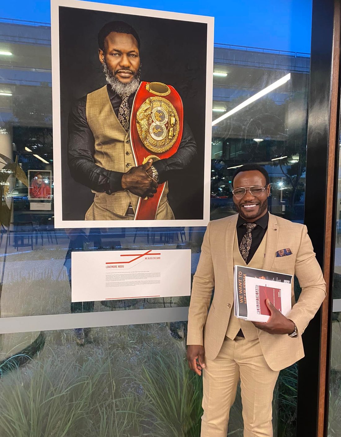 Lovemore Ndou standing beside a portrait of himself holding an IBF world championship belt