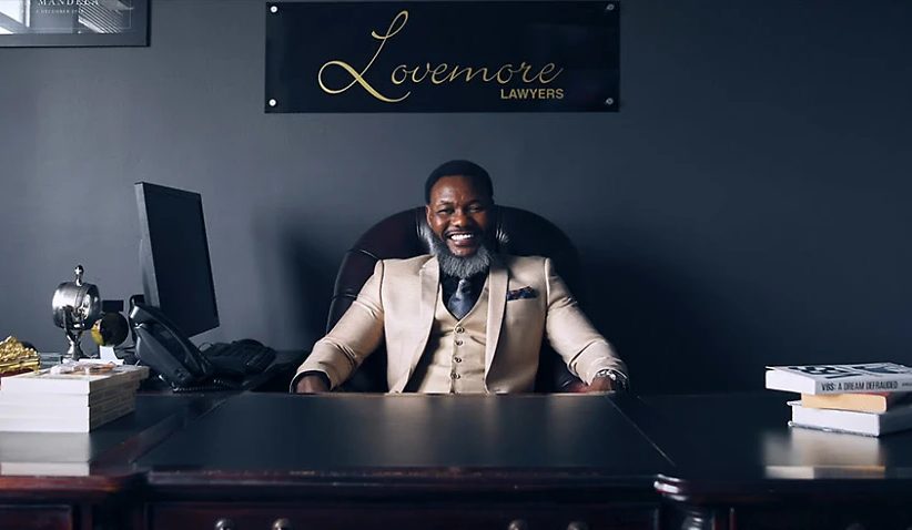 Lovemore Ndou at his desk beneath the Lovemore Lawyers sign